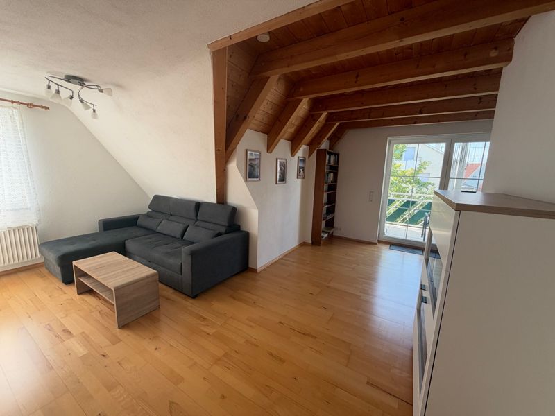 Wohnzimmer mit Sofa, Holzdecke und Balkontür